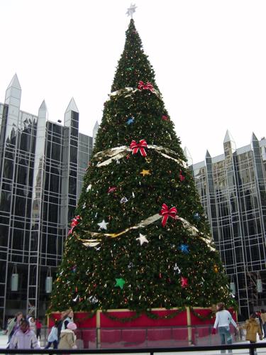 large outdoor Christmas tree with ice skaters skating around it
