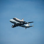 Space Shuttle Endeavour on top of NASA's Shuttle Carrier Aircraft, in the air, from the ground.