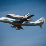 Space Shuttle Endeavour on top of NASA's Shuttle Carrier Aircraft, in the air, from the ground.