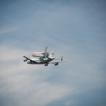 Space Shuttle Endeavour on top of NASA's Shuttle Carrier Aircraft, in the air, from the ground.